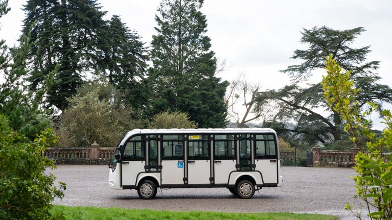 White shuttle bus outside a stately home